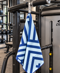 A blue and white patterned gym towel hangs from a pull-up bar on a Cybex strength training machine inside a gym.