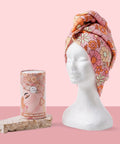 Floral patterned hair wrap on a mannequin head with packaging on a pink background