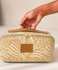 A zebra-print cosmetic bag with a tan leather handle and a brown leather brand patch reading 'SKY GAZER', held by a person's hand against a neutral beige background.