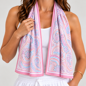 A woman wearing a white tank top and white drawstring shorts, with a pink indigenous cooling towel draped around her neck like a scarf. 